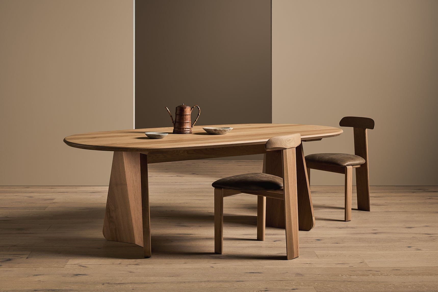 Wooden dining table with two chairs in a minimalistic room.